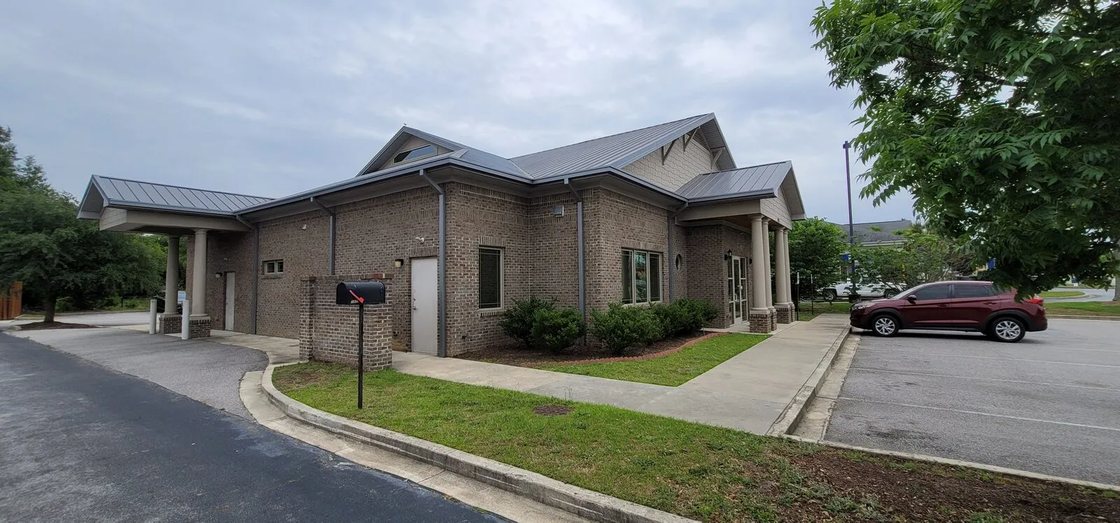 Completed brick commercial bank building with standing-seam metal roof and drive-thru canopy