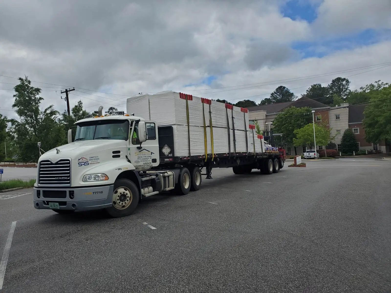 Flatbed truck delivering commercial roofing materials to a job site