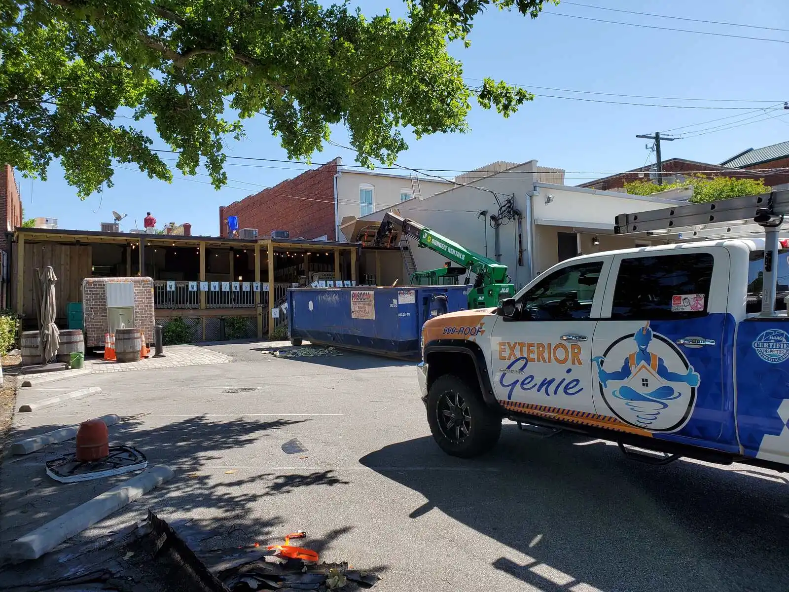 Commercial roofing project in progress at a downtown restaurant with crane and dumpster