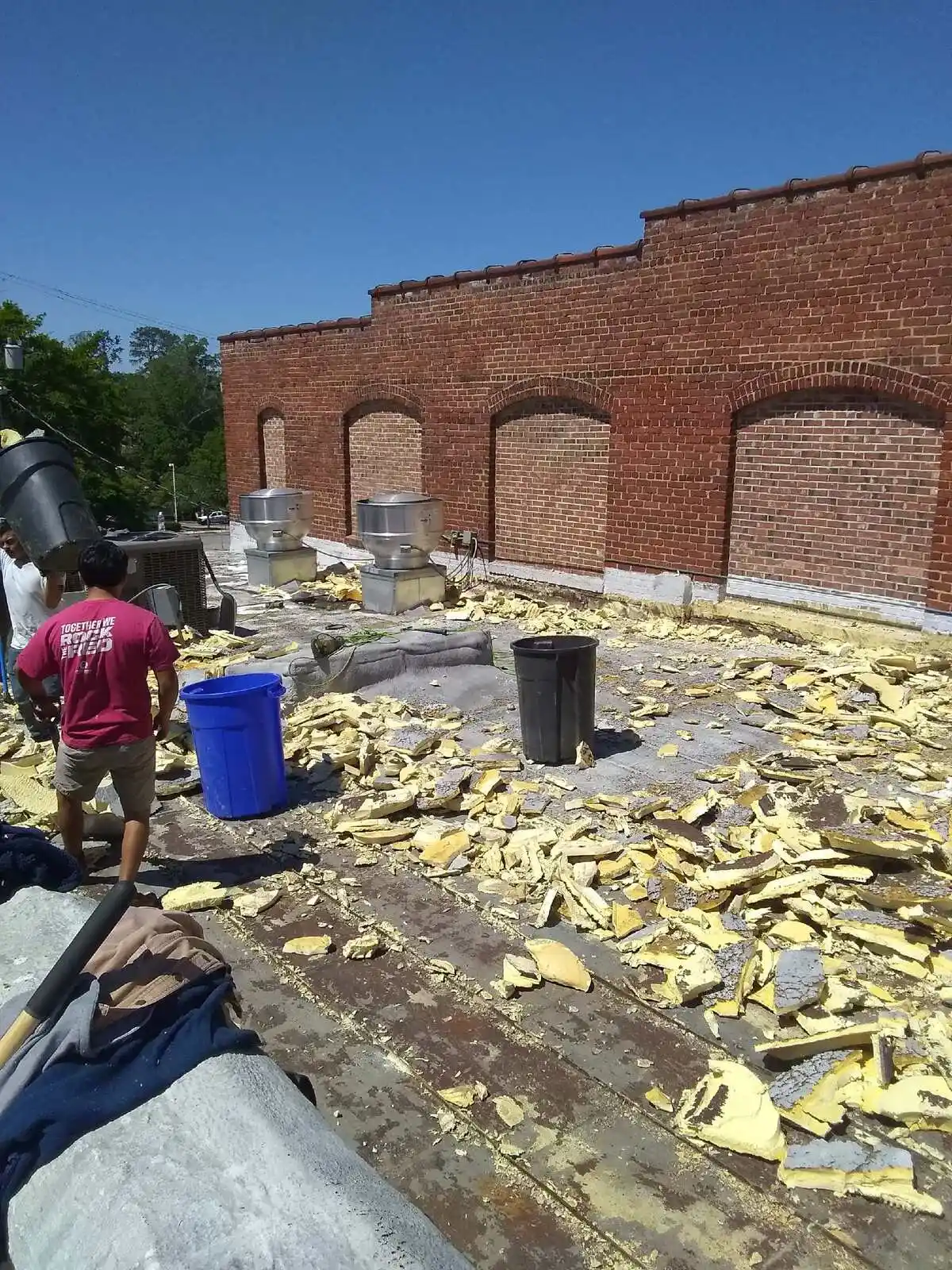 Crew tearing off old commercial flat roof insulation and membrane