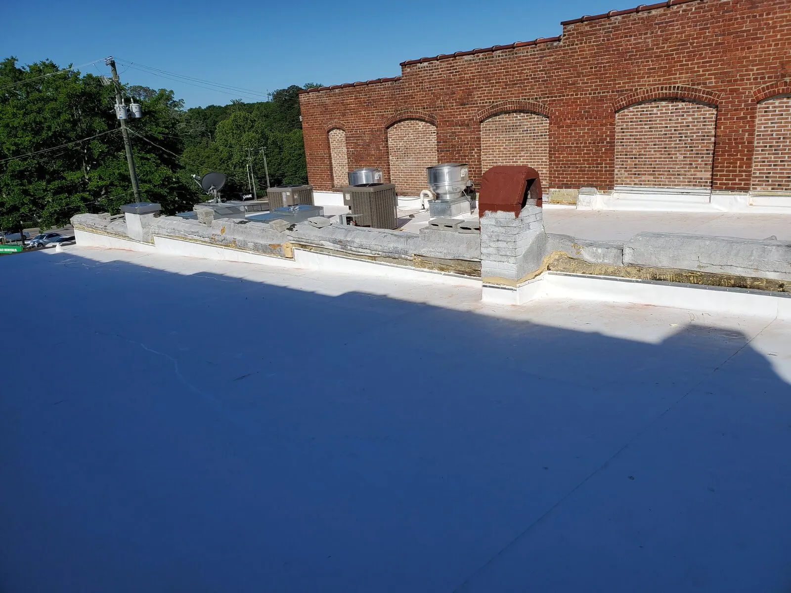 Completed TPO membrane flat roof installation on a commercial brick building